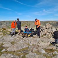 Andy S, Andy L, Henry, Lewis and Lucie on the summit of Sgor an Lochain Uaine with the midges, The Sphinx snow patch in the background